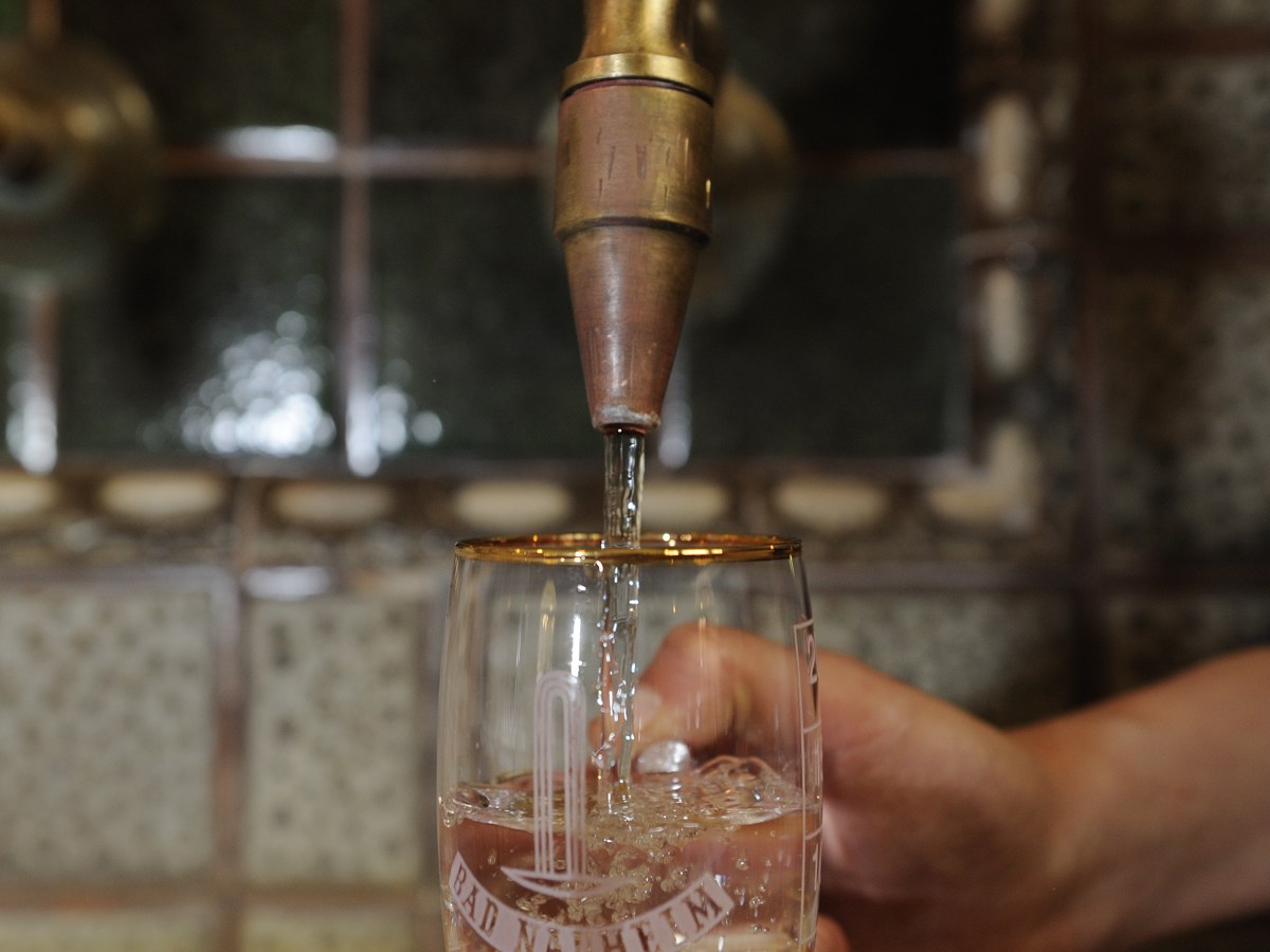 A glass being filled with mineral water at the historic Kurbrunnen spring in Bad Nauheim
