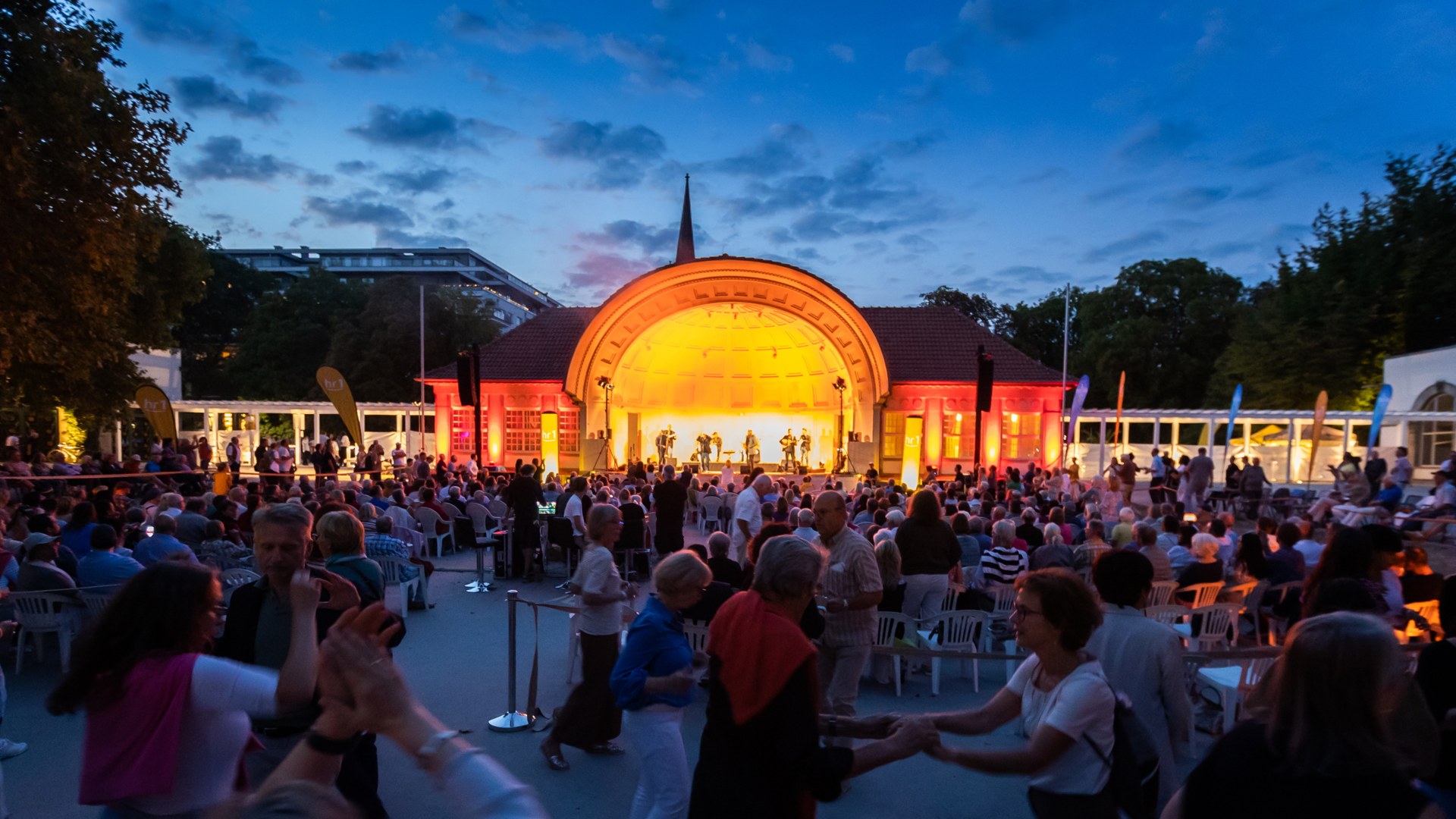 An evening summer concert and dance in Bad Nauheim, with crowds gathered under a lit pavilion